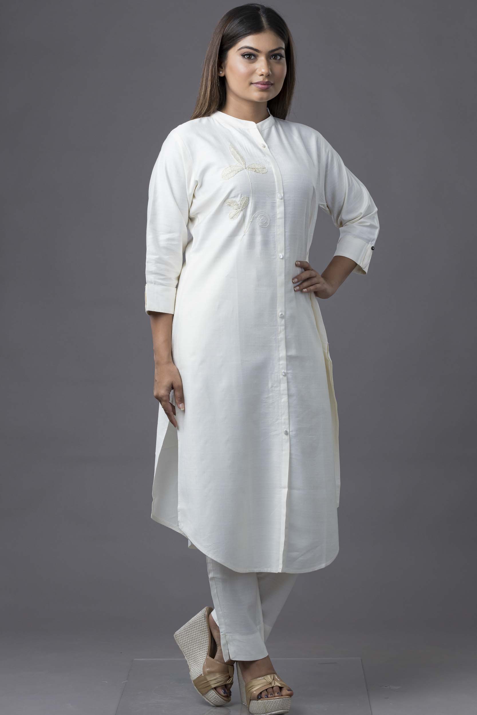 Woman wearing a white kurta with white pants against a gray background